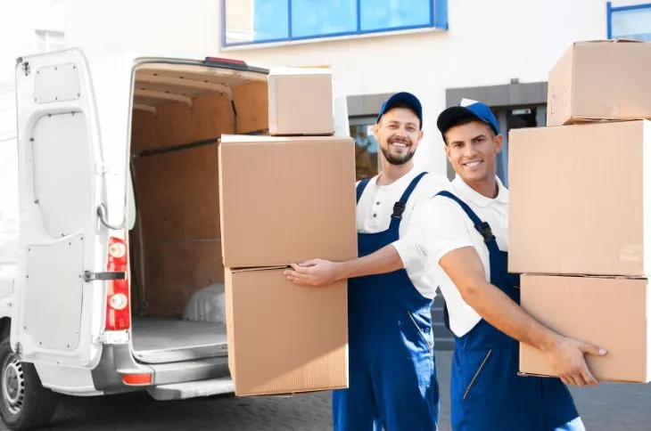 Umzugshelfer tragen Kartons aus Transporter Umzugshelfer tragen Kartons aus Transporter